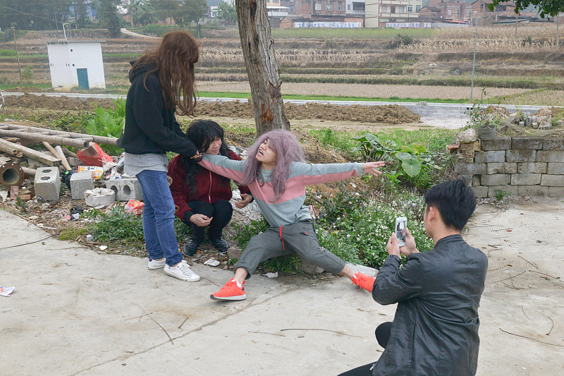 快手红人蹲在树下拍段子，图片来源@视觉中国
