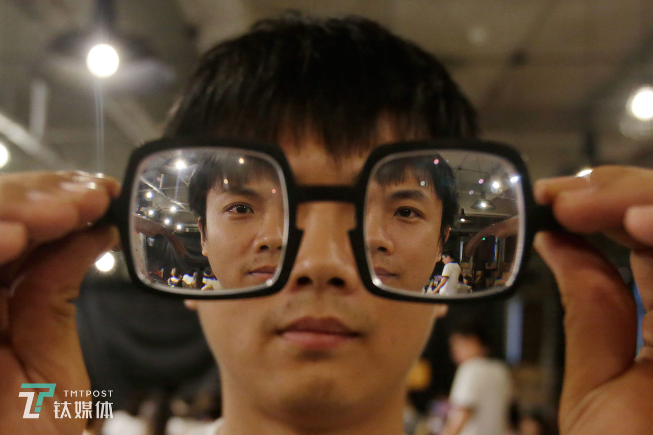 9月18日，北京，脱口秀演员小块举起眼镜供钛媒体《在线》拍摄肖像。